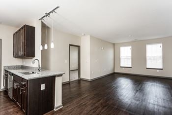 An empty living room and kitchen with wood flooring and a counter top